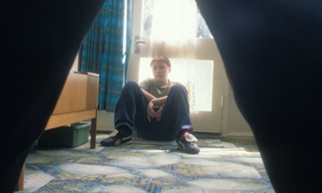 young boy sitting by door being threatened by adult man