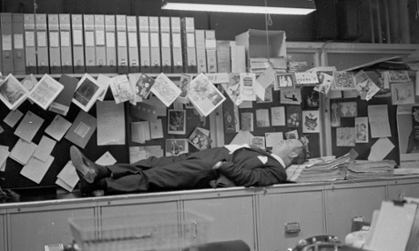 An office worker taking a nap on top of the filing cabinet