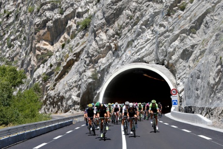 The peloton emerge from a tunnel as the race hits the Alps.