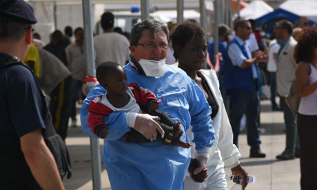 A doctor carries a child and holds the hand of her mother as they arrive in Palermo, Italy, with 717 other migrants this month.