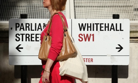 A pedestrian walking past a sign on Whitehall, London.