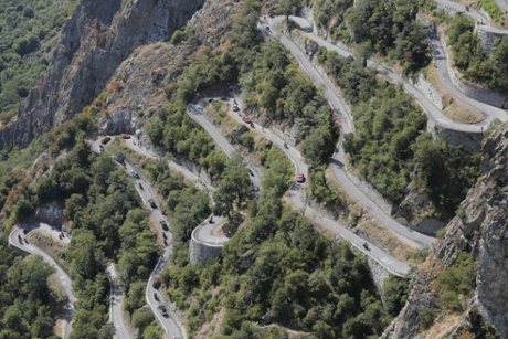 Riders, team cars and press motorcycles climb the Lacets de Montvernier during the stage.