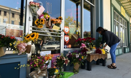 A local resident leaves flowers at a makeshift memorial outside of a store owned by one of the victims, Jillian Johnson, on Friday in Lafayette, Louisiana. shooting theater