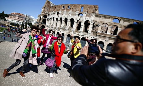 Tourists pose in front of the Colosseum in Rome