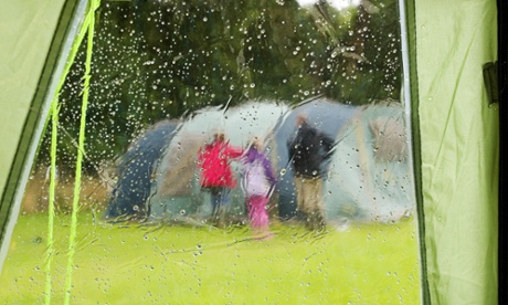 Family erecting tent on rainy campsite Pembrokeshire Wales UK.