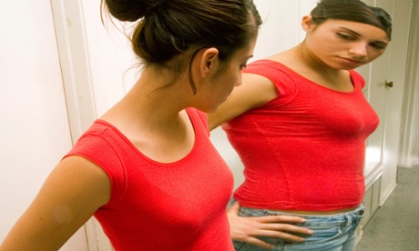 girl looking in mirror and seeing a distorted image of herself