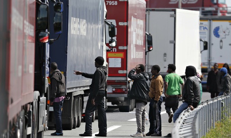 Migrants gather near a line of lorries in Calais