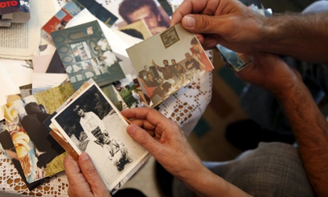 Hajra Catic and Edmin Jakubovic look at pictures of Hajra's son at her home in Srebrenica.