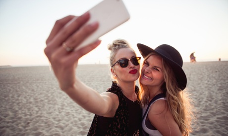 Female friends photographing themselves on smartphone