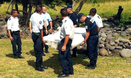 Police and gendarmes carry a piece of debris from an unidentified aircraft found in the coastal area of Saint-Andre de la Reunion, in the east of the French Indian Ocean island of La Reunion, on July 29, 2015.