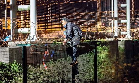 A migrant climbs a security fence