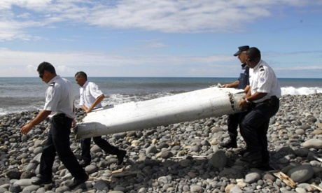 Officers carrying pieces of aircraft debris washed ashore on Réunion.