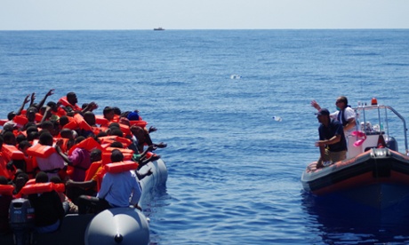 Moas rescuers throw bottles of water to refugees in a rubber raft near Malta in August 2014.