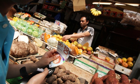 A man at a greengrocer pays with Brixton pounds