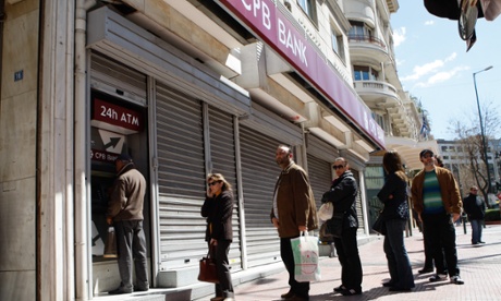 People queue to use an ATM in Athens, Greece.