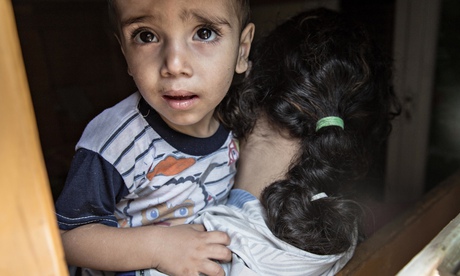 The wide-eyed, bewildered face of a small boy being held by his young mother
