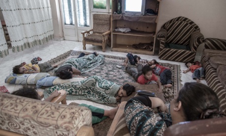 Children lying on a large rug on the floor, some with a blanket over them, at Hope VIllage