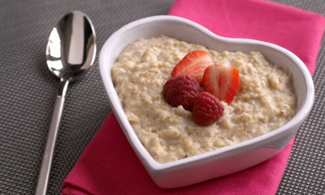 Porridge in a heart shaped bowl with fresh strawberries on top
