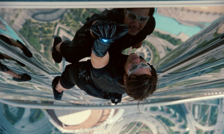 In a still photo from the film Mission Impossible: Ghost Protocol, Tom Cruise climbs the outside of the Burj Khalifa Tower in Dubai as we look down from above him to the ground far below.