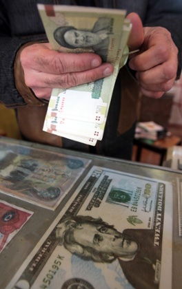 An Iraqi money dealer counts Iranian rial banknotes with a portrait of Iran’s late founder of Islamic Republic, Ayatollah Khomeini.