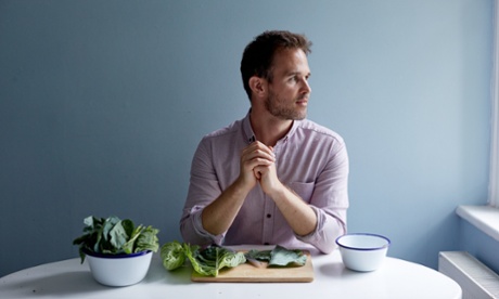 ed smith sits at a table with a chopping board of fresh greens in front of him