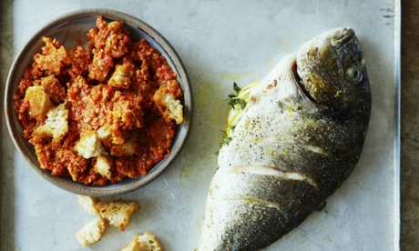 A dish of red pepper romesco sauce with rough breadcrumbs crumbled in, alongside a roasted whole sea bream with a slashed and seasoned skin. 