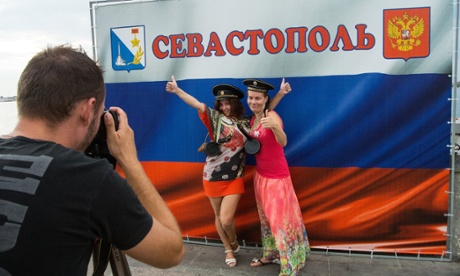 Women in Crimea pose for a picture next to a Russian flag with the word Sevastopol written on it. Ukraine