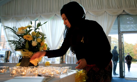 A woman lights a candle at the British Muslim Heritage Centre in Manchester before the start of memorial service for the murdered British hostage, Alan Henning. 