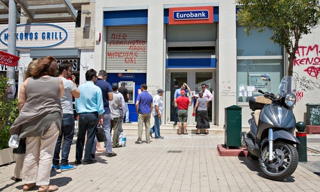 Customers queue to use a cash machine at a Eurobank branch in Athens in July