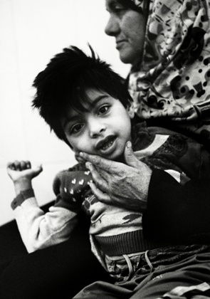 Maryam, in the arms of her grandmother, Manzuma. She is like a rag-doll with painfully sad eyes.