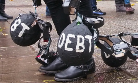Student protester with heavy black balls strapped to legs to represent the burden of student debt.