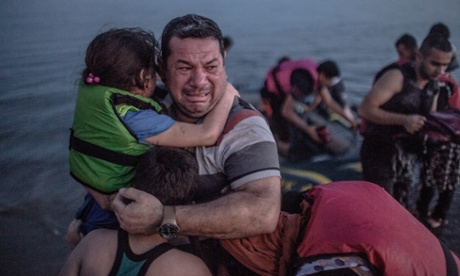Syrian refugee Laith Majid holds his son and daughter, after arriving via a flimsy inflatable boat crammed with about 15 men, women and children on the shore of the island of Kos in Greece on 15 August 2015