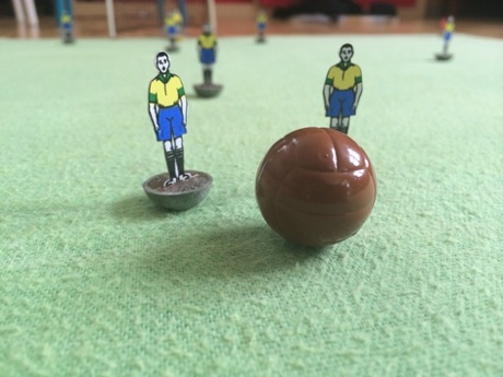 A box of old Subbuteo teams from the 1950s and 1960s made of celluloid and card players with coloured bases, chalk for the pitch, fish-net goals and a (large!) brown leather football. Brazil are the stand-out team.
