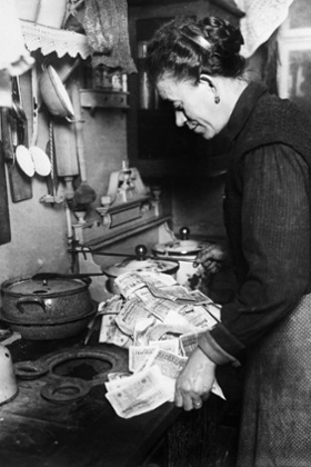 a woman uses banknotes to light stove in Berlin c.1922.