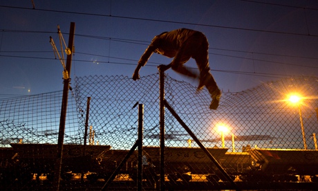 A migrant jumps a fence in calais