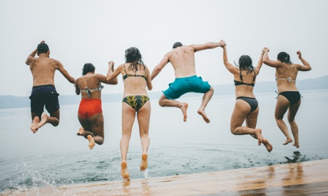 Holidaymakers jump from a jetty into the water.