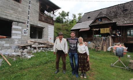 One of the Vasiles with his grandparents next to old and new houses.