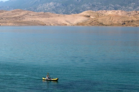 Sophie paddles in a canoe along the shoreline of Pag island.