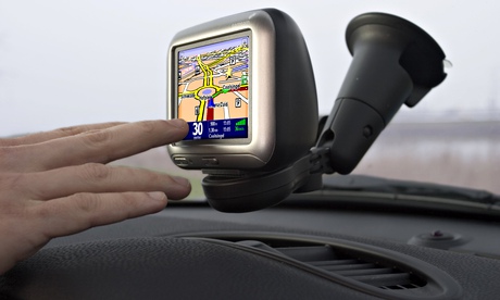 a hand reaching to a satnav on a dashboard