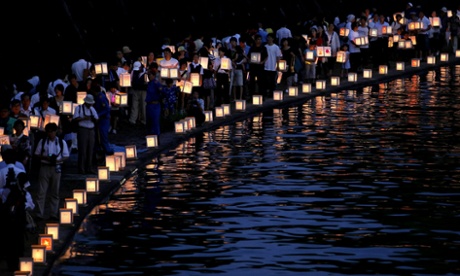 People carry paper lanterns to release onto the Urakami River for peace and the atomic bomb victims as they walk along the river in Nagasaki, Japan.