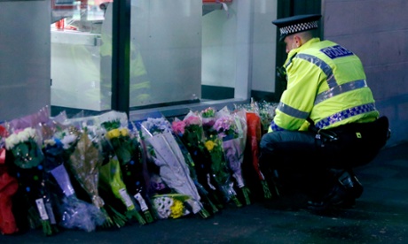 A police officer with flowers laid near the bin lorry crash scene in George Square, Glasgow, in December 2014.