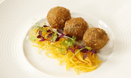 Three golfball-sized balls of haggis next to shredded turnip topped with delicate violet petals