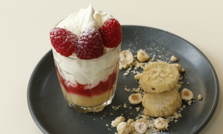Small glass of raspberry and lemon trifle with crumbling biscuits on a plate