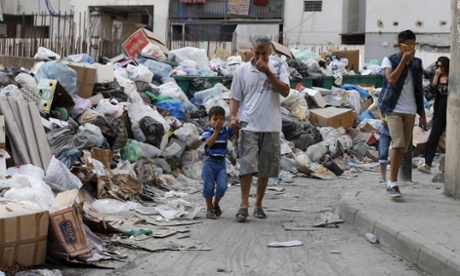 Residents cover their noses as they walk past garbage