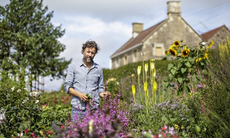 Dan Pearson, bearded, squinting, standing in his farm's flower garden