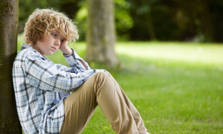 young boy sitting by tree alone