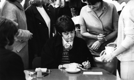 Paul McCartney, of The Beatles, is besieged by autograph hunters in a London Transport Workers' canteen.
