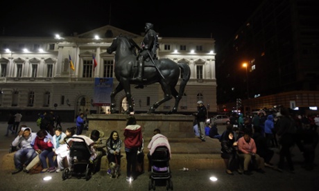 Residents sit next to an equestrian statue in Santiago’s main square after the earthquake struck. The powerful earthquake caused buildings to sway in Santiago and other cities and sent people running into the streets.