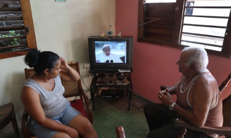 People watch as the arrival of Pope Francis is shown on television in Santiago de Cuba, Cuba.