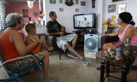 People watch as the arrival of Pope Francis is shown on television in Santiago de Cuba, Cuba.